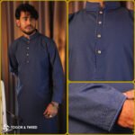Man wearing a navy jacquard Pakistani Panjabi with textured fabric, styled collar, and buttoned placket, standing in a studio setting.