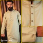 Man wearing a light beige jacquard Pakistani Panjabi with textured fabric, styled collar, and buttoned placket, standing in a studio setting.