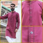 Man wearing a maroon jacquard Pakistani Panjabi with textured fabric, styled collar, and buttoned placket, standing in a studio setting.