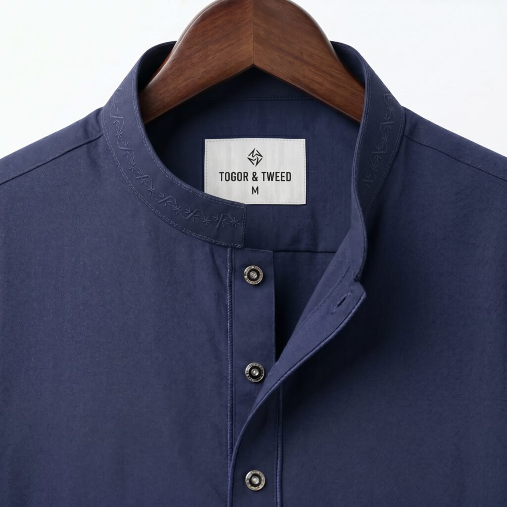 Top view of folded Togor & Tweed Navy Pakistani Jacquard Panjabi highlighting the textured fabric, tonal embroidered collar, and metallic buttons on a white background