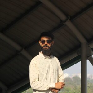 Man wearing a white premium textured striped shirt with sunglasses, standing outdoors near greenery and a sidewalk, styled for a modern yet traditional look.