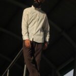 Man wearing a white premium textured striped shirt with sunglasses, standing outdoors near greenery and a sidewalk, styled for a modern yet traditional look.