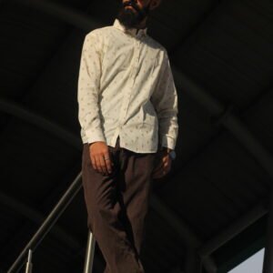 Man wearing a white premium textured striped shirt with sunglasses, standing outdoors near greenery and a sidewalk, styled for a modern yet traditional look.