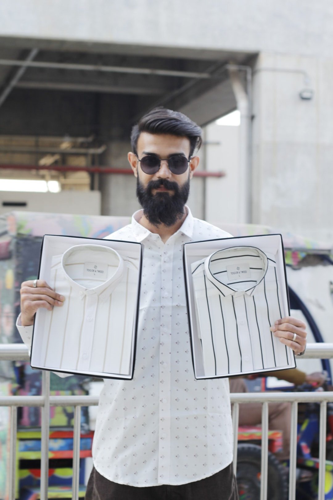 Man wearing a white premium textured striped shirt with sunglasses, standing outdoors near greenery and a sidewalk, styled for a modern yet traditional look.