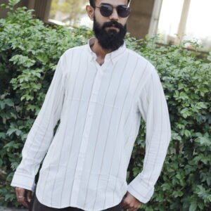 Man wearing a white premium textured striped shirt with sunglasses, standing outdoors near greenery and a sidewalk, styled for a modern yet traditional look.