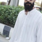 Man wearing a white premium textured striped shirt with sunglasses, standing outdoors near greenery and a sidewalk, styled for a modern yet traditional look.